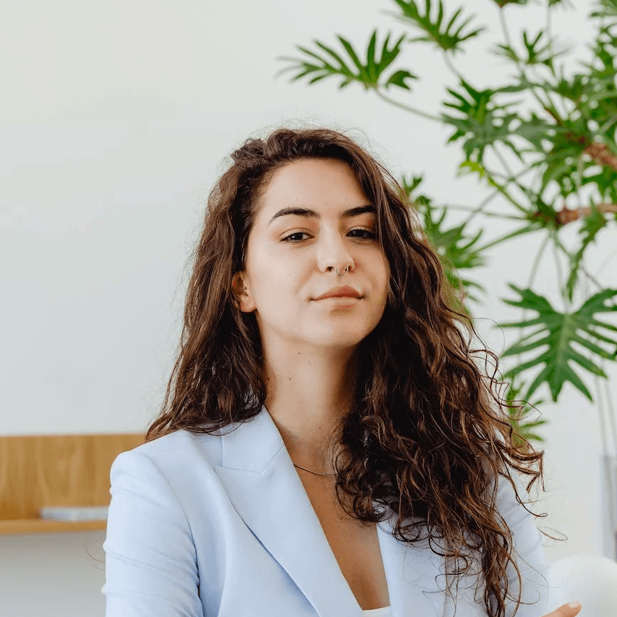 Eine Frau in Weiß in einem Büro mit einer Pflanze dahinter.