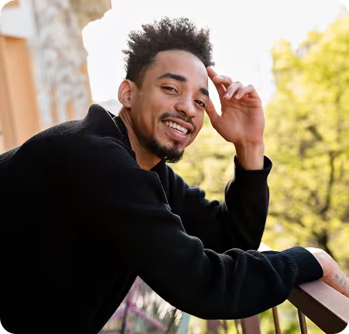 Lächelnder Mann auf Balkon, deutet auf Stressreduktion durch Cannabis.